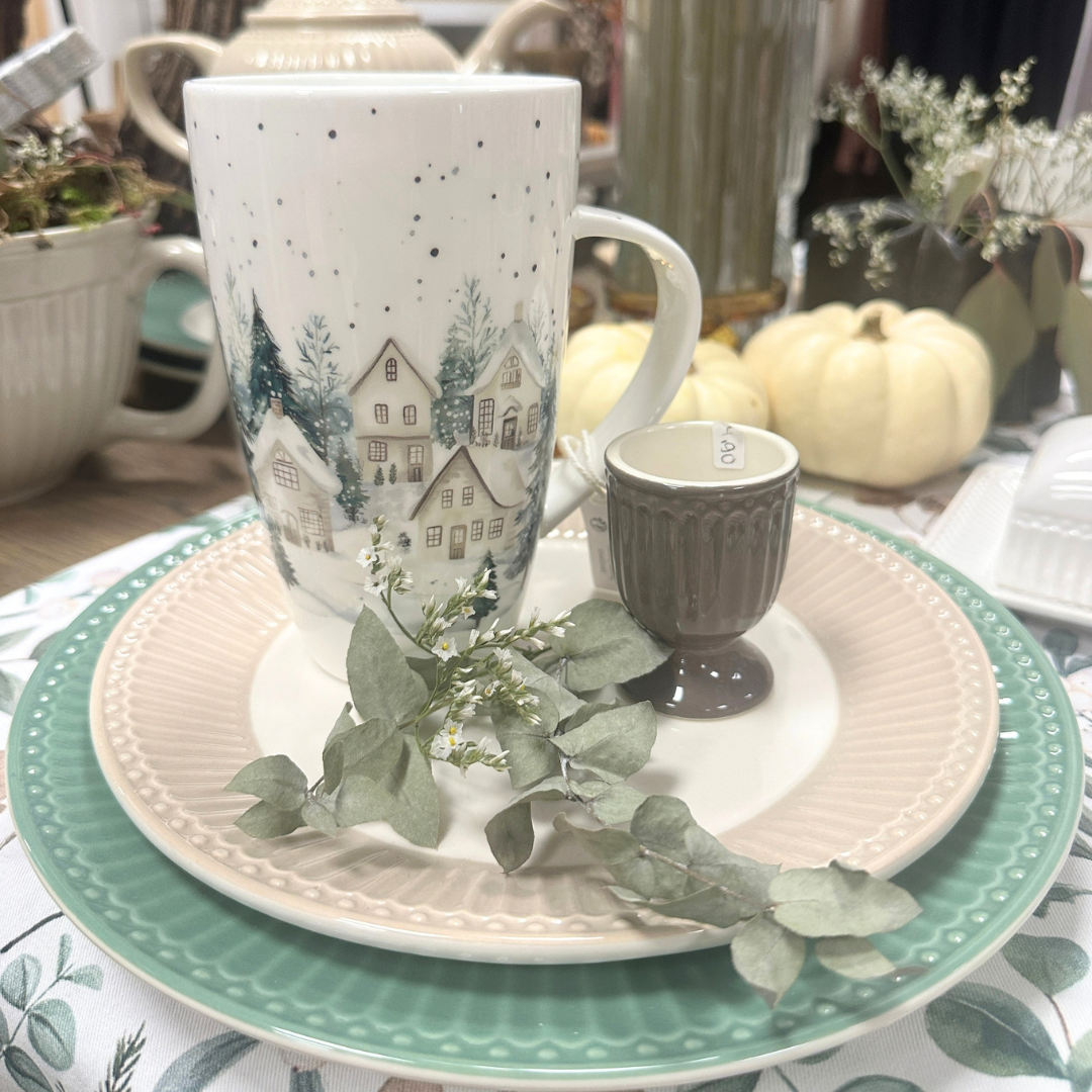 Ambiente Becher Snowy Houses aus Fine Bone China mit verschneitem Winterdorf, kleinen Häusern, grünen Tannen und Schneeflocken auf Greengate Teller Alice creamy fudge und Teller Alice dusty green schön dekoriert