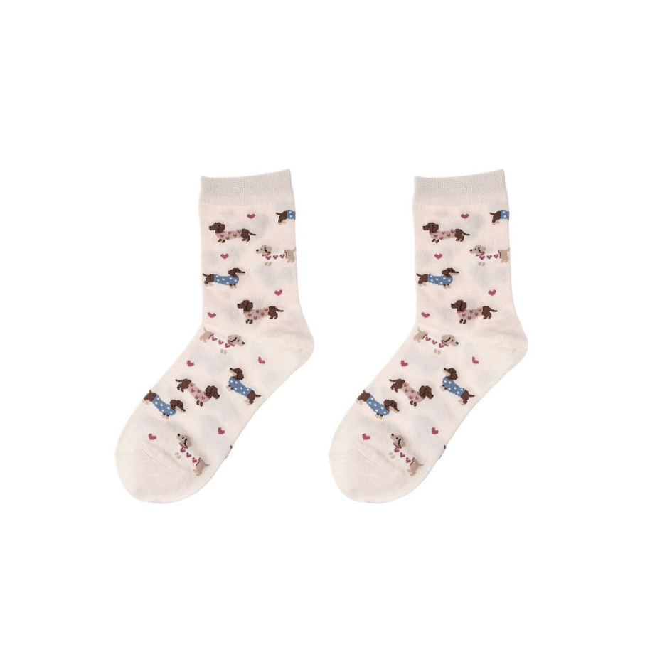 Cremefarbene Damen Socken mit Dackel-Motiv, kleinen Hunden in rosa und blauen Pullovern sowie rosa Herzchen, Größe 36–41.