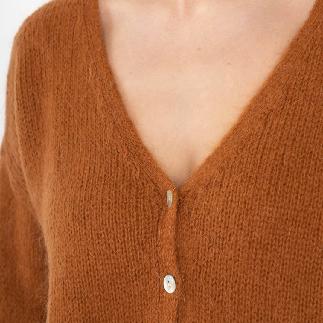 Detailansicht Ocker- und senfgelbe Damen-Strickjacke mit Mohair, V-Ausschnitt, langen Ärmeln und zarten perlmuttfarbenen Knöpfen.