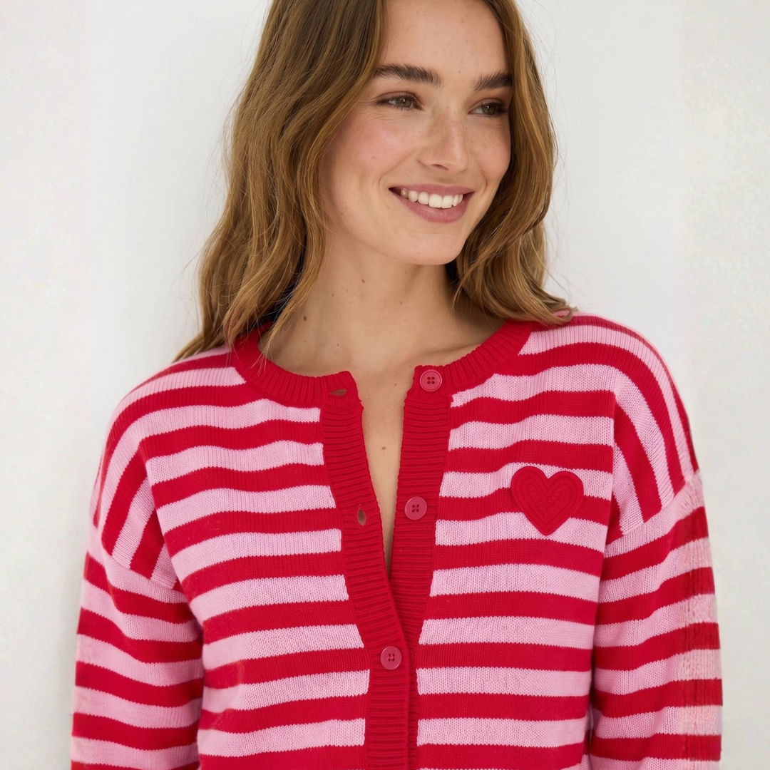 Gestreifte Strickjacke Mindy in Rot und Rosa mit Knopfleiste, Rundhalsausschnitt und rotem Herzmotiv auf der Brust.