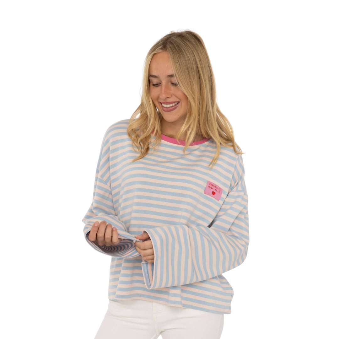 Zwillingsherz Langarmshirt Perfectly Imperfect in Hellblau und Creme gestreift mit pinkem Ausschnitt und kleinem Statement-Patch.