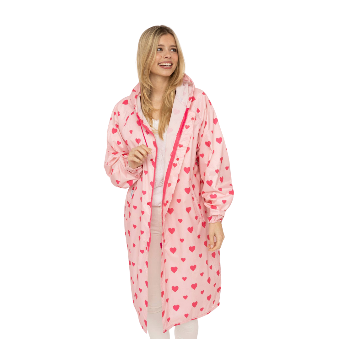 Zwillingsherz Regenmantel Love in Rosa mit pink-rotem Herzchenprint, Kapuze, langen Ärmeln und langem Schnitt.